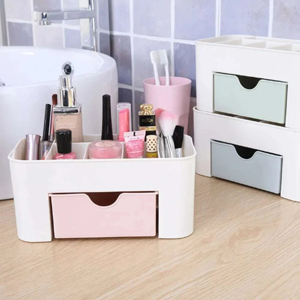 Plastic makeup organizer with multiple compartments and drawers for cosmetics storage in pink, blue, and white colors on a wooden surface near a sink