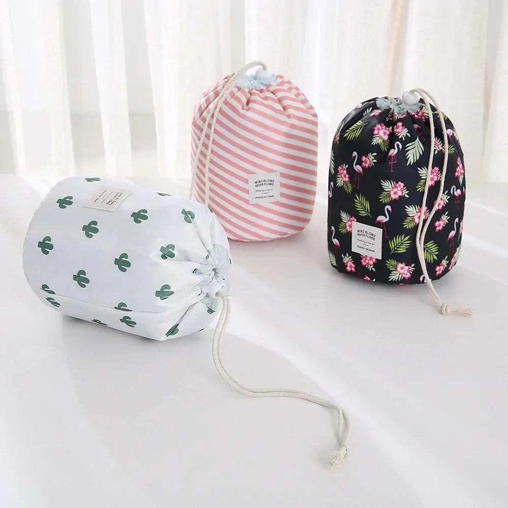Set of three waterproof makeup bags in cactus, pink stripes, and flamingo floral patterns with drawstring closures on a white surface